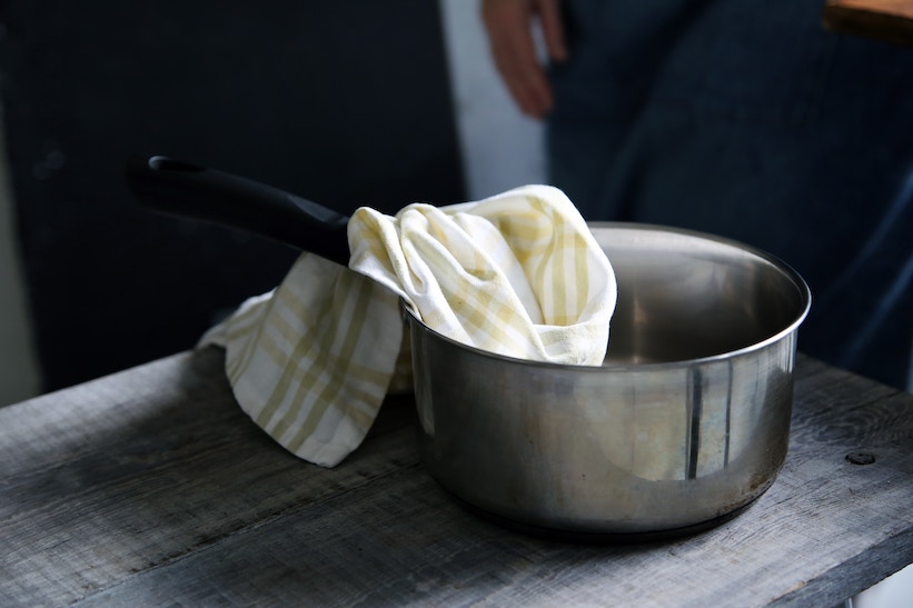 A pan with a kitchen towel on a table